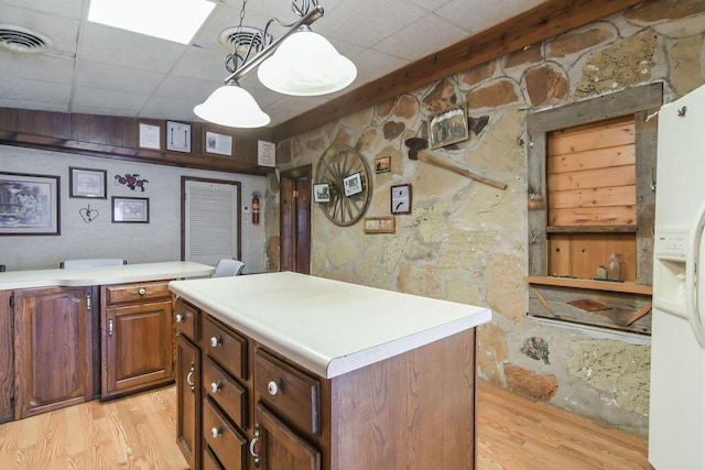 kitchen with a center island, light wood-style flooring, white refrigerator with ice dispenser, and light countertops