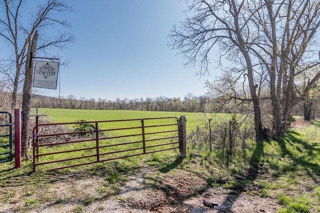 view of gate with a rural view, a yard, and fence