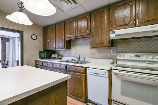 kitchen featuring wallpapered walls, white appliances, light countertops, under cabinet range hood, and a sink