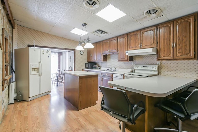kitchen with electric range, under cabinet range hood, white fridge with ice dispenser, and wallpapered walls