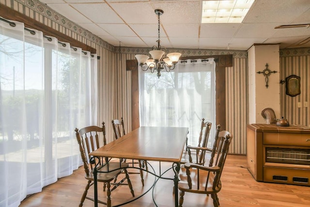 dining area with a paneled ceiling, an inviting chandelier, light wood-style floors, and wallpapered walls