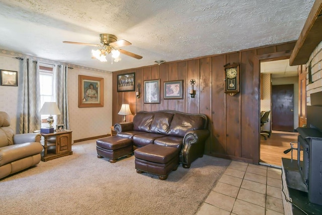 living area featuring light tile patterned floors, a textured ceiling, a ceiling fan, light carpet, and baseboards
