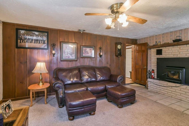 carpeted living area with wood walls, ceiling fan, tile patterned floors, and a textured ceiling