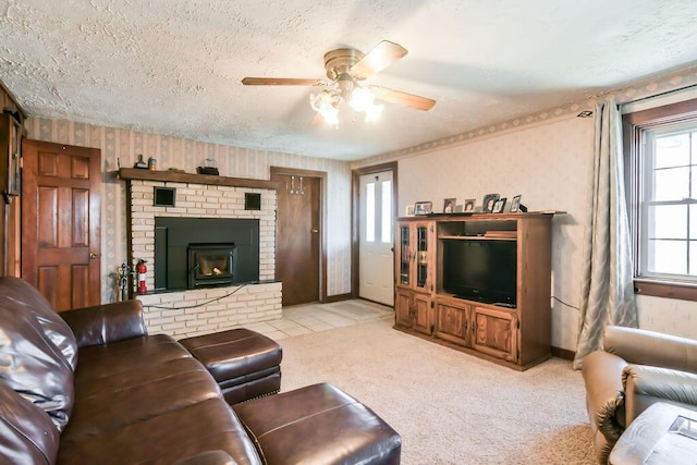 living room with ceiling fan, a brick fireplace, light carpet, and a textured ceiling