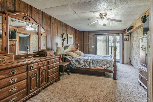 bedroom with wooden walls, light colored carpet, and a ceiling fan