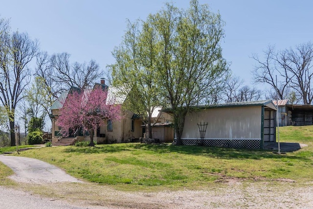 view of front facade featuring an outbuilding, a chimney, a front lawn, and a pole building