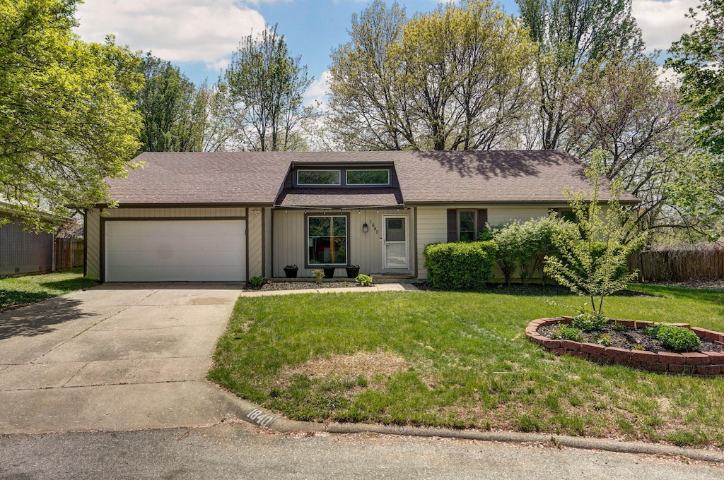 view of front of house with a garage, a front lawn, concrete driveway, and fence