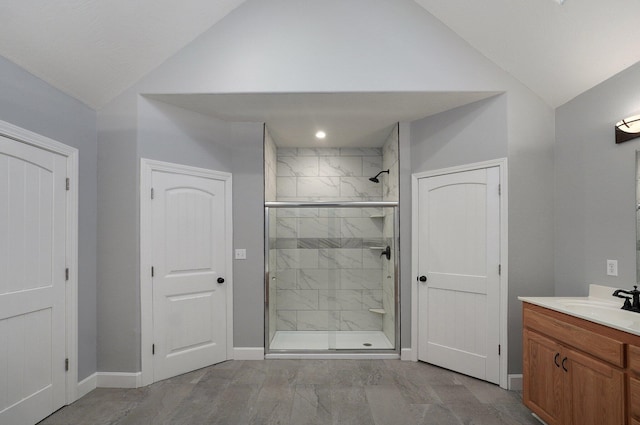 full bathroom featuring vanity, baseboards, a stall shower, and lofted ceiling