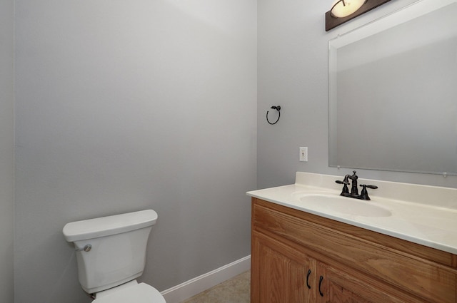bathroom featuring toilet, vanity, and baseboards