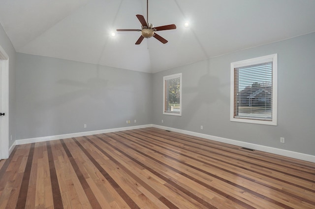 spare room featuring wood finished floors, ceiling fan, baseboards, and high vaulted ceiling