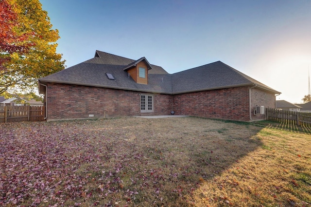 rear view of property featuring french doors, fence, and a yard