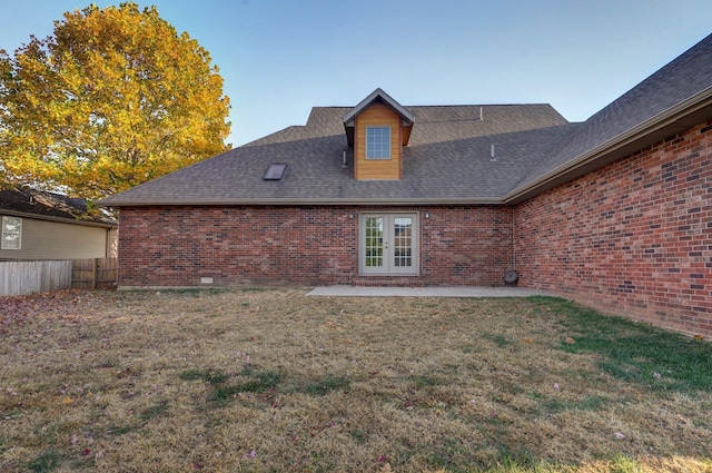 rear view of house with french doors, a patio area, brick siding, fence, and a lawn