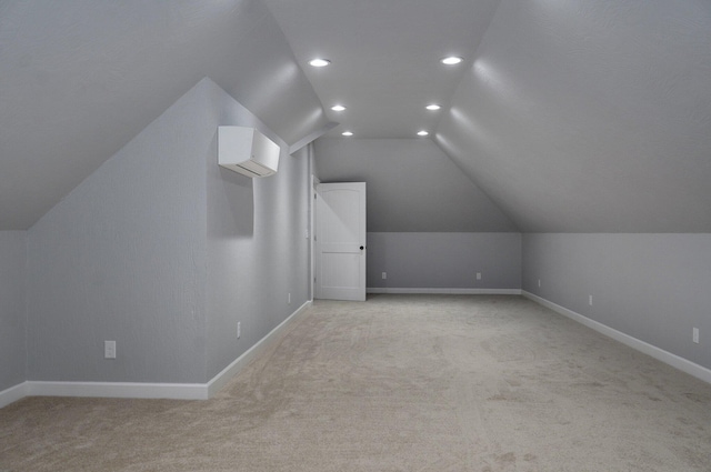 additional living space with light carpet, a wall mounted AC, baseboards, and vaulted ceiling