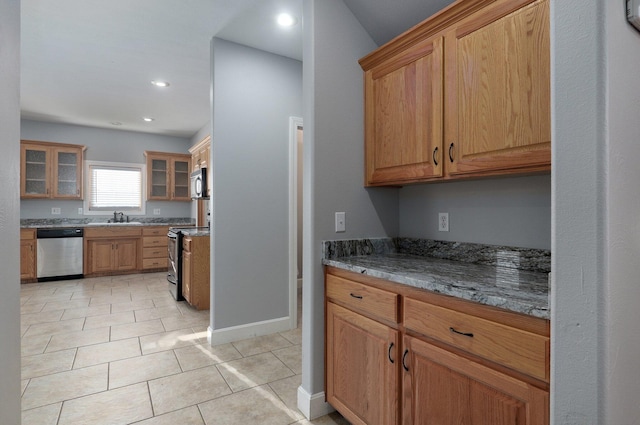kitchen featuring stone countertops, appliances with stainless steel finishes, light tile patterned flooring, and glass insert cabinets