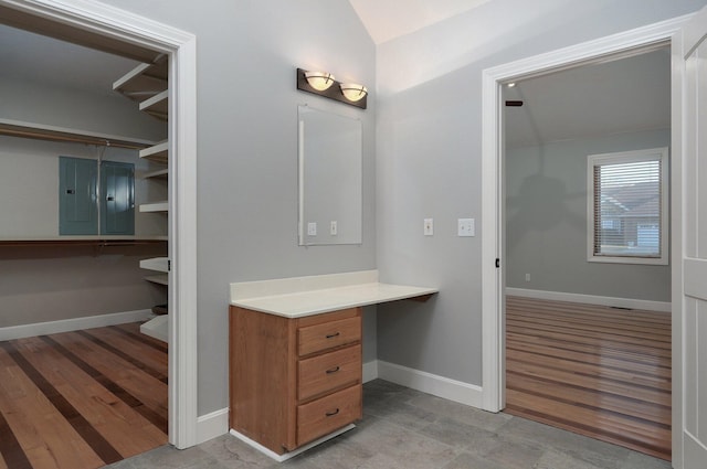 bathroom featuring electric panel, baseboards, wood finished floors, and lofted ceiling
