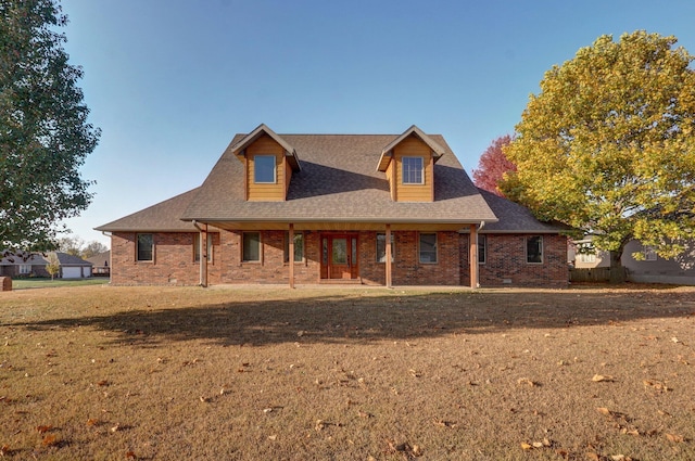 view of front of house with a front yard, brick siding, and roof with shingles
