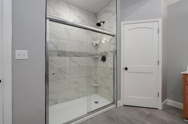 bathroom featuring vanity, baseboards, and a stall shower