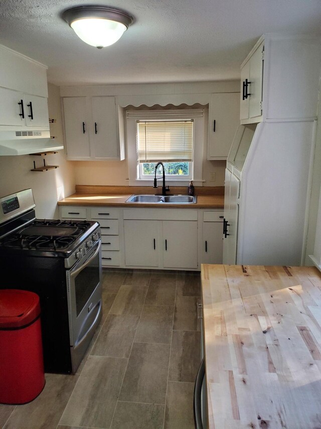 2111 N Grant Ave, Springfield, MO 65803 - kitchen featuring butcher block counters, white cabinets, under cabinet range hood, a sink, and stainless steel gas range oven