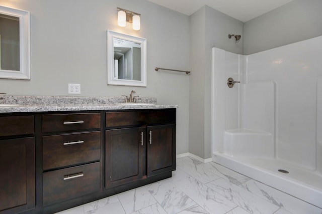 bathroom with baseboards, double vanity, a shower, marble finish floor, and a sink
