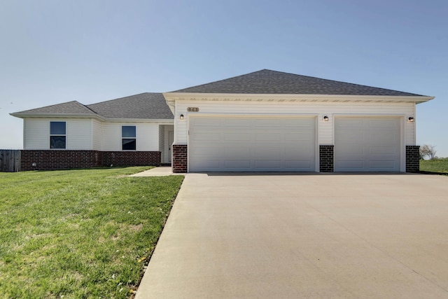 view of front of property with roof with shingles, a front yard, brick siding, an attached garage, and concrete driveway
