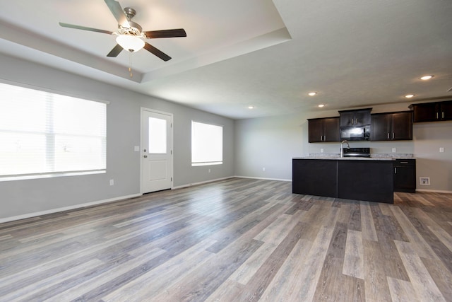 kitchen with open floor plan, black microwave, recessed lighting, and wood finished floors