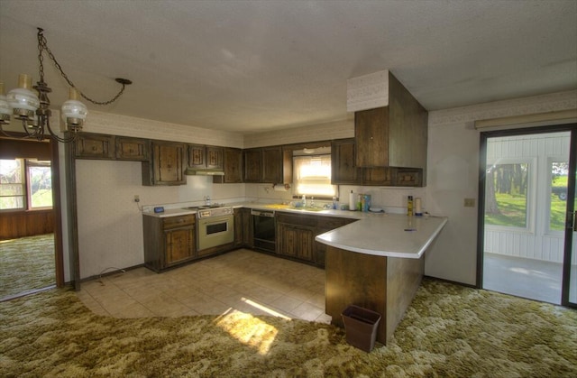 kitchen featuring light countertops, plenty of natural light, black dishwasher, and a peninsula