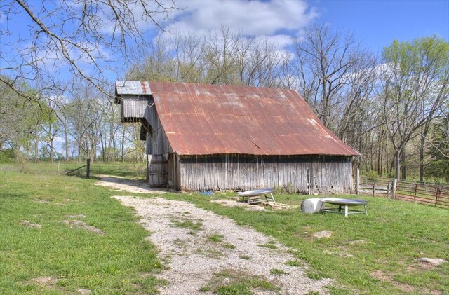 view of barn featuring a yard and fence