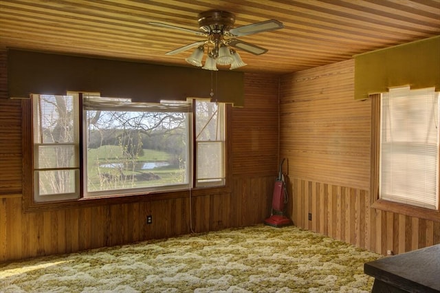 empty room featuring wood walls, wood ceiling, carpet floors, and ceiling fan