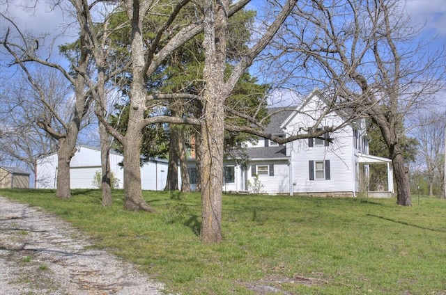 view of front of home featuring a front yard, gravel driveway, and a shingled roof