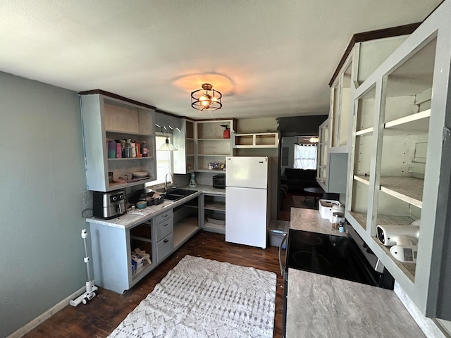 kitchen with black microwave, dark wood-style floors, freestanding refrigerator, open shelves, and a sink