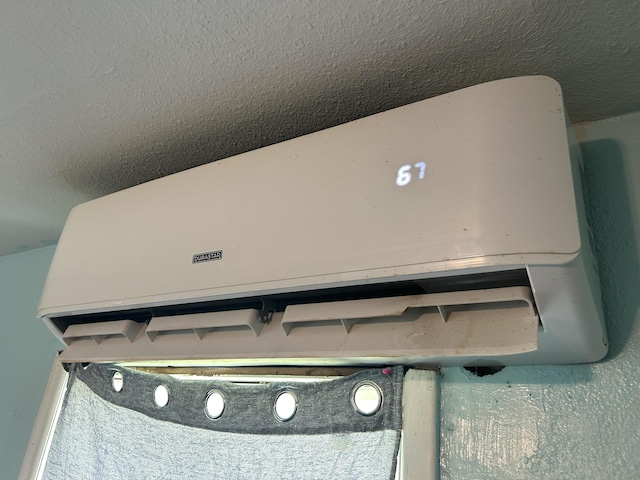room details with a wall mounted air conditioner and a textured ceiling
