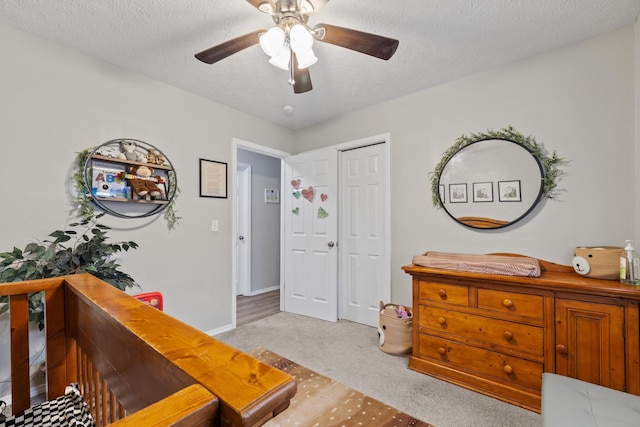 bedroom featuring light carpet, a textured ceiling, a ceiling fan, and a closet