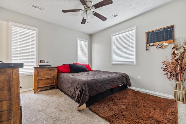 bedroom featuring visible vents, light colored carpet, multiple windows, and a textured ceiling