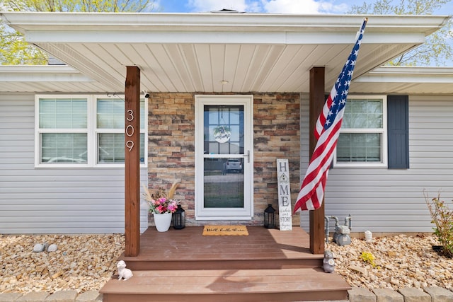 doorway to property featuring a porch and stone siding