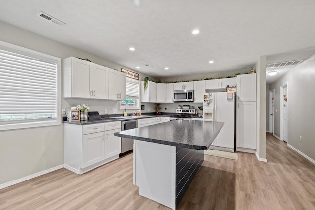 kitchen with visible vents, dark countertops, light wood-style floors, and stainless steel appliances