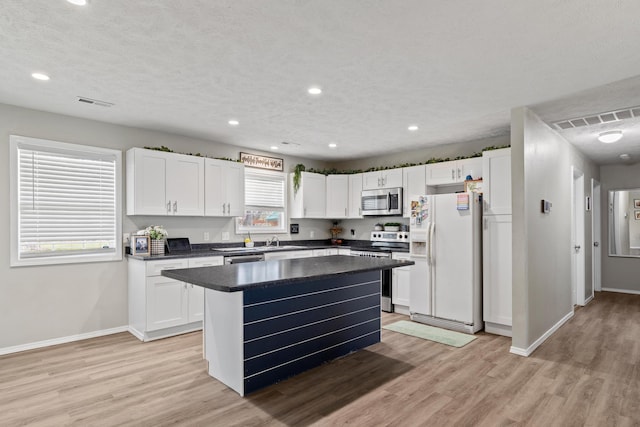 kitchen featuring baseboards, dark countertops, visible vents, stainless steel appliances, and a sink