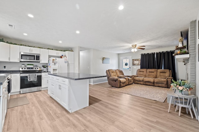kitchen featuring dark countertops, open floor plan, light wood-style flooring, and appliances with stainless steel finishes