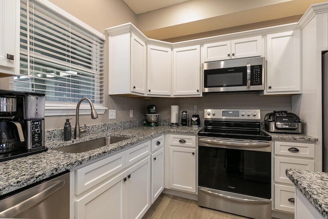 760 W Stewart St, Bolivar, MO 65613 - kitchen with appliances with stainless steel finishes, a sink, white cabinetry, and light wood-style flooring