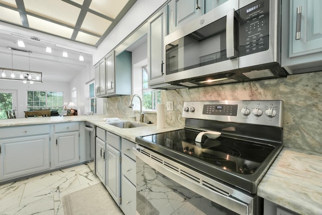 kitchen with tasteful backsplash, a sink, light countertops, appliances with stainless steel finishes, and marble finish floor