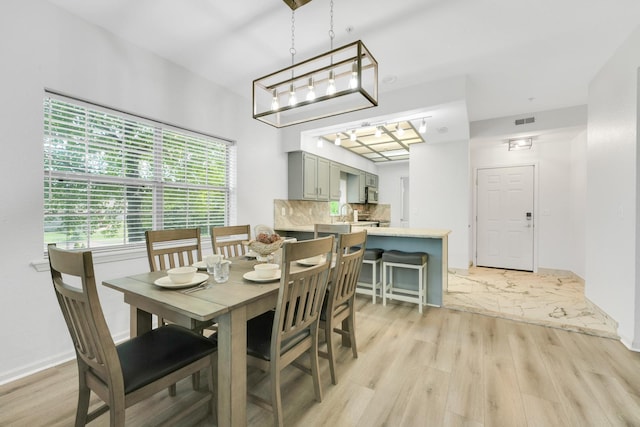 dining room featuring light wood-style flooring, baseboards, and visible vents