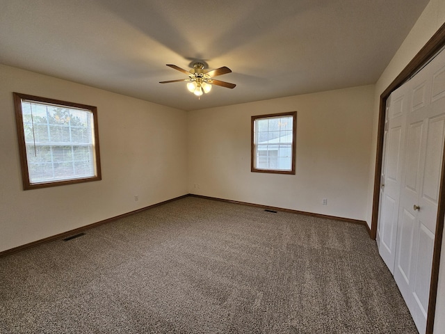 unfurnished bedroom featuring dark colored carpet, a closet, and baseboards