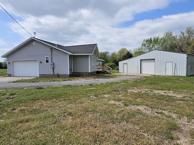 exterior space featuring a garage, a yard, an outbuilding, and a shingled roof