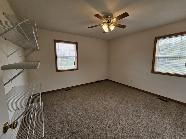 spare room with carpet floors, a ceiling fan, visible vents, and baseboards