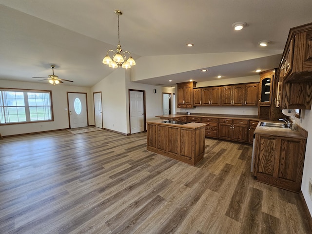 kitchen with vaulted ceiling, a center island, a sink, ceiling fan with notable chandelier, and dark wood finished floors