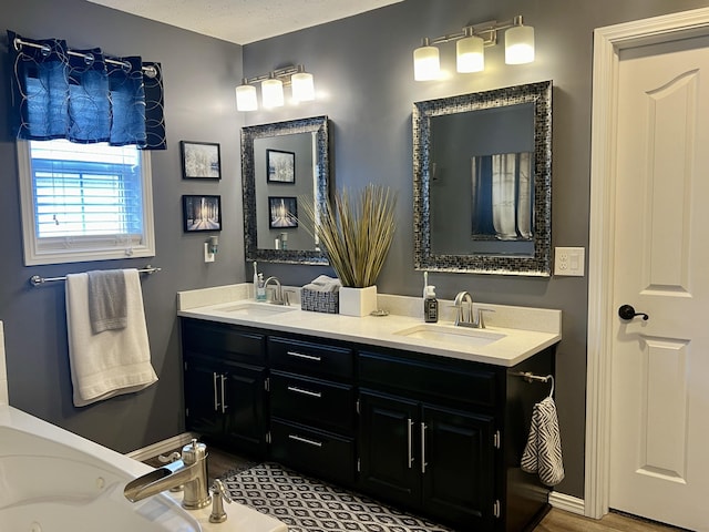 full bath featuring double vanity, baseboards, a sink, and a tub with jets