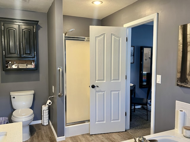 bathroom featuring visible vents, toilet, wood finished floors, a stall shower, and baseboards