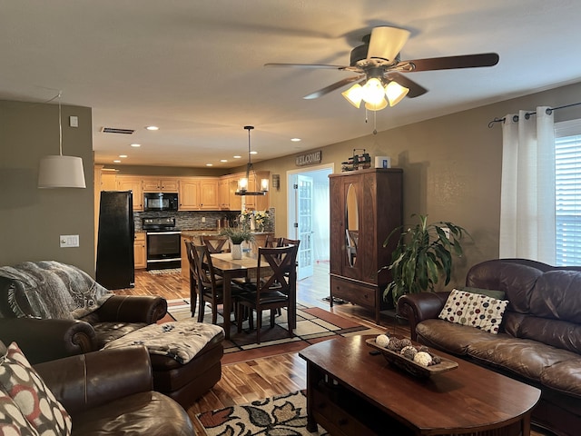 living area featuring light wood finished floors, a ceiling fan, visible vents, and recessed lighting