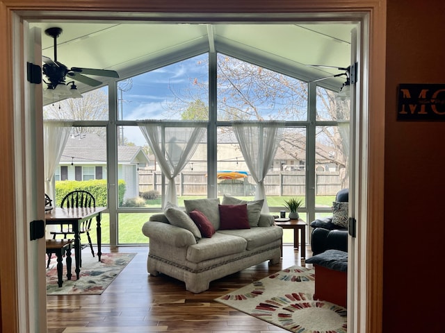 living area with ceiling fan, hardwood / wood-style floors, lofted ceiling, and a wall of windows