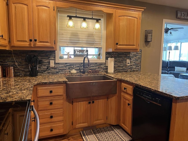 kitchen featuring dark stone counters, tasteful backsplash, a peninsula, black appliances, and a sink