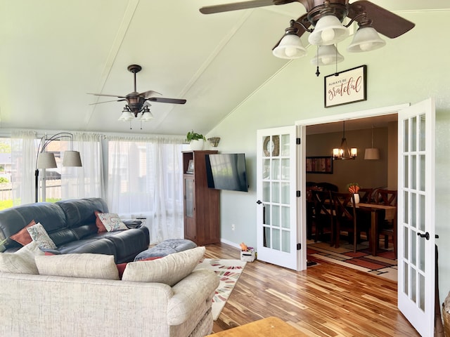living room with french doors, wood finished floors, vaulted ceiling, and ceiling fan with notable chandelier